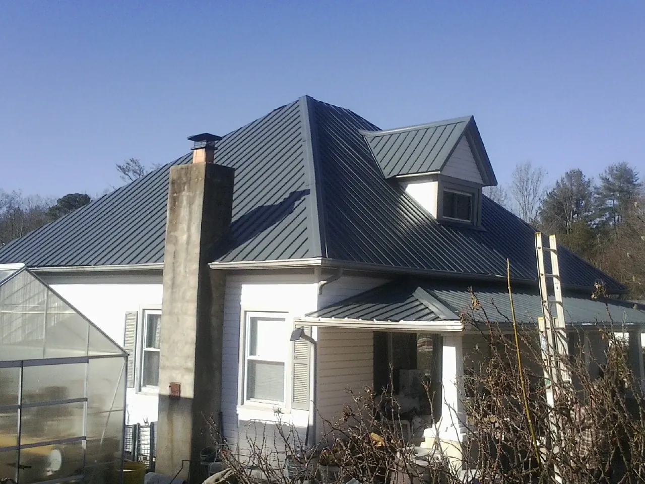 Dark blue standing seam metal roof on a white farmhouse with dormer — Slate & Tile Roof Repair by Roofing Brothers in Huntertown
