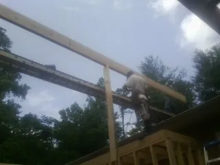 Carpenter setting a ridge beam over a new addition frame — Ice Dam Removal by Roofing Brothers in Huntertown