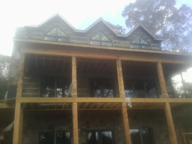 Dormers and porch framing on a large log home under construction — Roof Coating work by our crew in Huntertown
