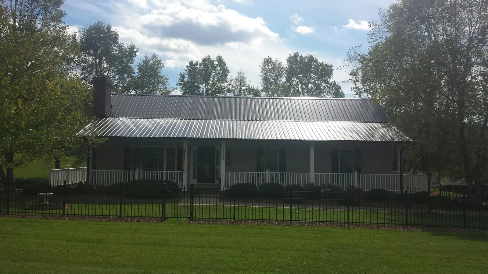 Gray metal roof on a brick ranch with a full width front porch — Gutter Guard Installation work by our crew in Huntertown