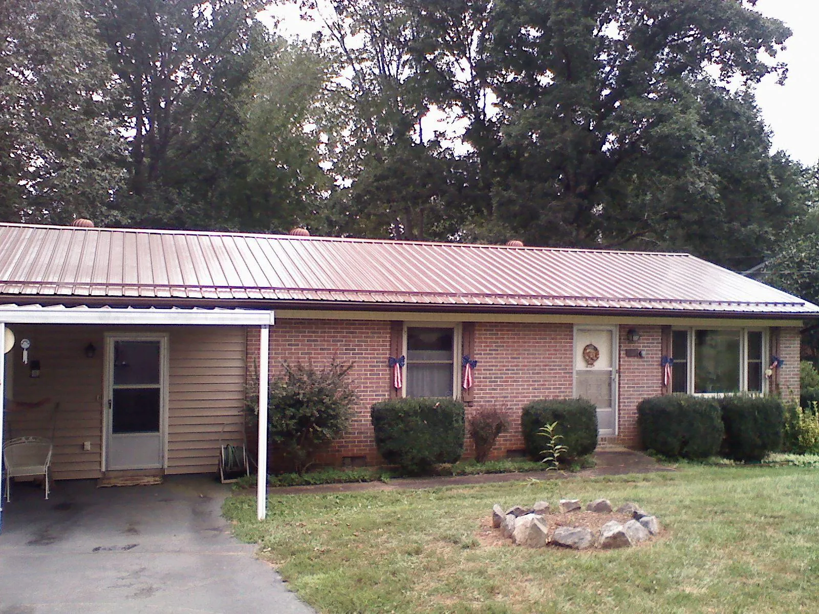 Bronze metal roof and carport on a brick ranch home — Roof Repair work by our crew in Huntertown