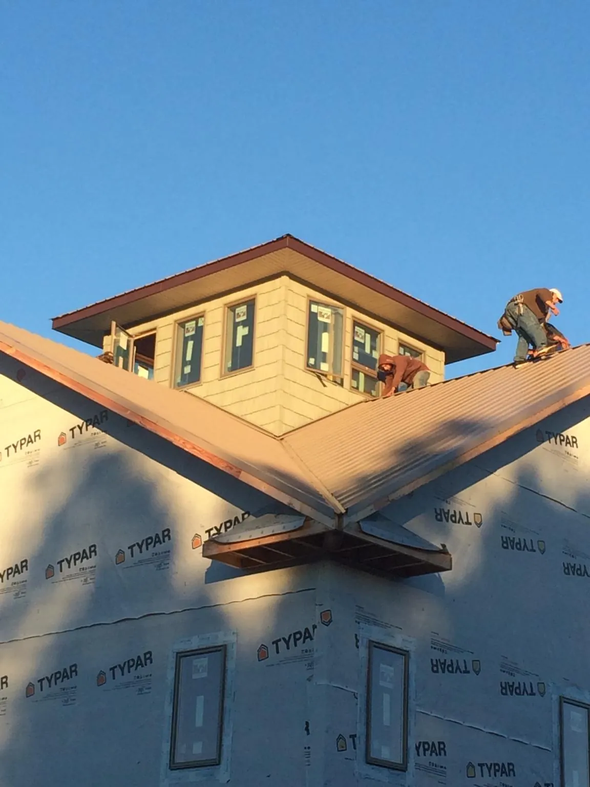 Roofers working around a rooftop cupola on a new metal roof at sunset — Roof Waterproofing in Huntertown by Roofing Brothers